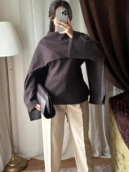 Blouse à cape noire portée avec un pantalon beige