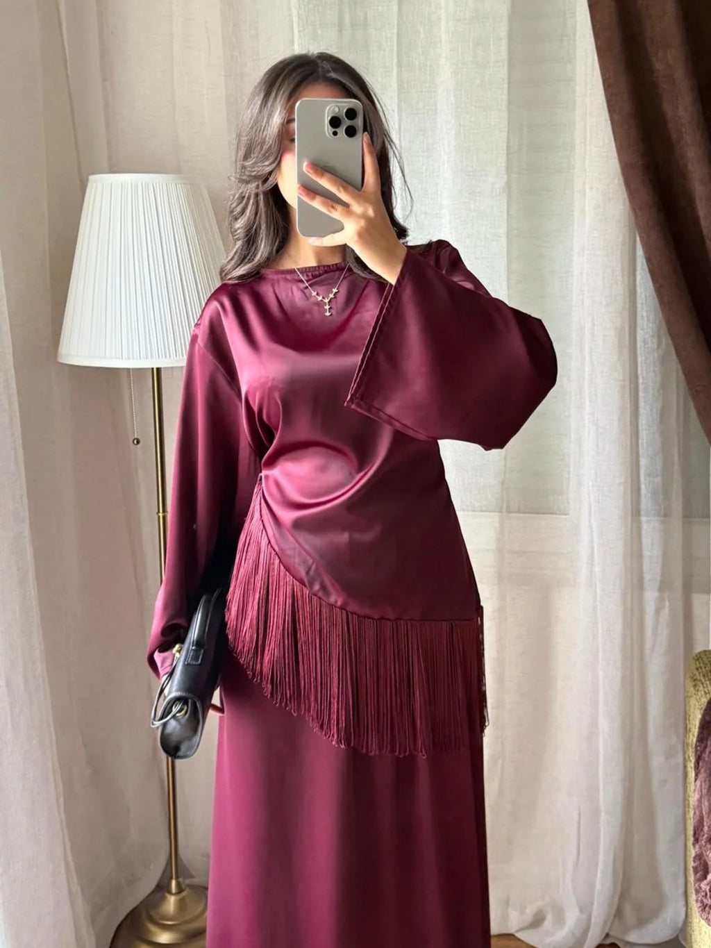 Blouse satinée bordeaux à franges portée avec une jupe longue