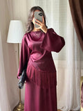 Blouse satinée bordeaux à franges portée avec une jupe longue