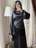 Blouse satinée noire à franges portée avec une jupe longue