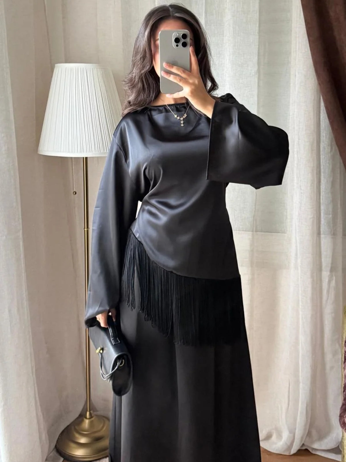 Blouse satinée noire à franges portée avec une jupe longue