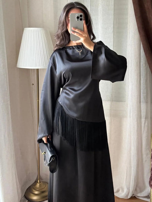 Blouse satinée noire à franges portée avec une jupe longue
