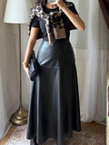 Jupe longue simili cuir noire portée avec un t-shirt noir