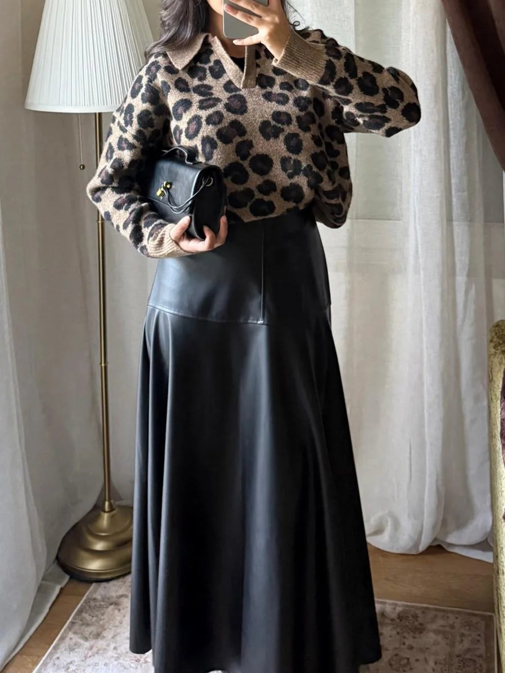 Jupe simili cuir noire associée à un pull léopard